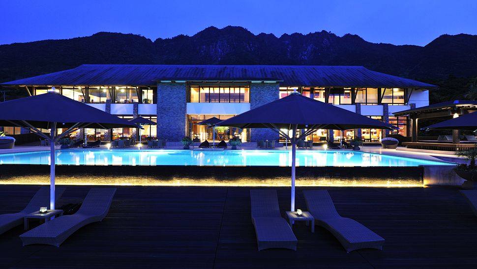 日本鹿儿岛县屋久岛 Sankara Hotel & Spa_008841-04-exterior-pool-umbrellas-mountain-backdrop-view.jpg