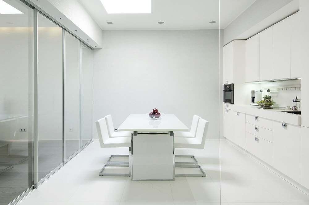 Kitchen-glass-walled-in-white-with-sleek-cabinetry-and-modern-dining-setting.jpg