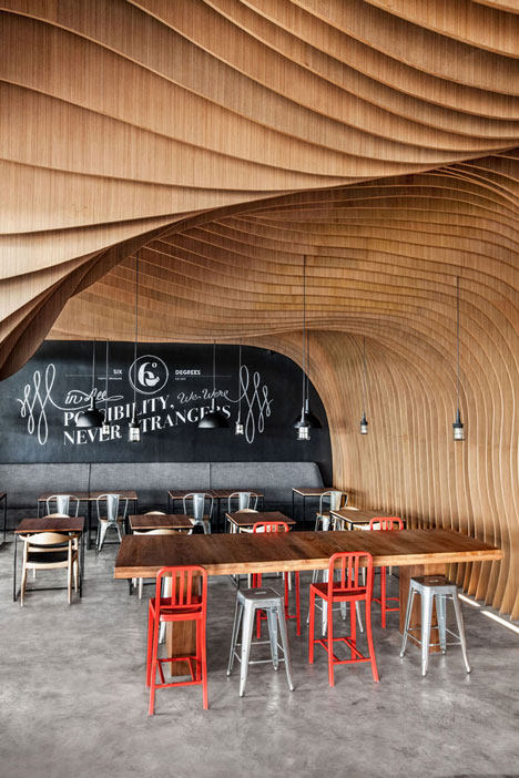 OOZN Design creates cavernous cafe in Jakarta using undulating timber slats_Undulating layers of timber create a cave-like interior inside this cafe in Indonesia by local studi ...