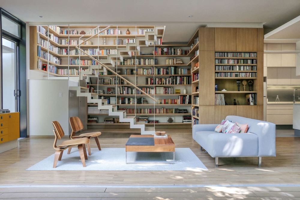 A Book Lover’s Dream House With Great Nature Views_wall-of-books-behind-staircase-Scandinavian-living-area.jpg